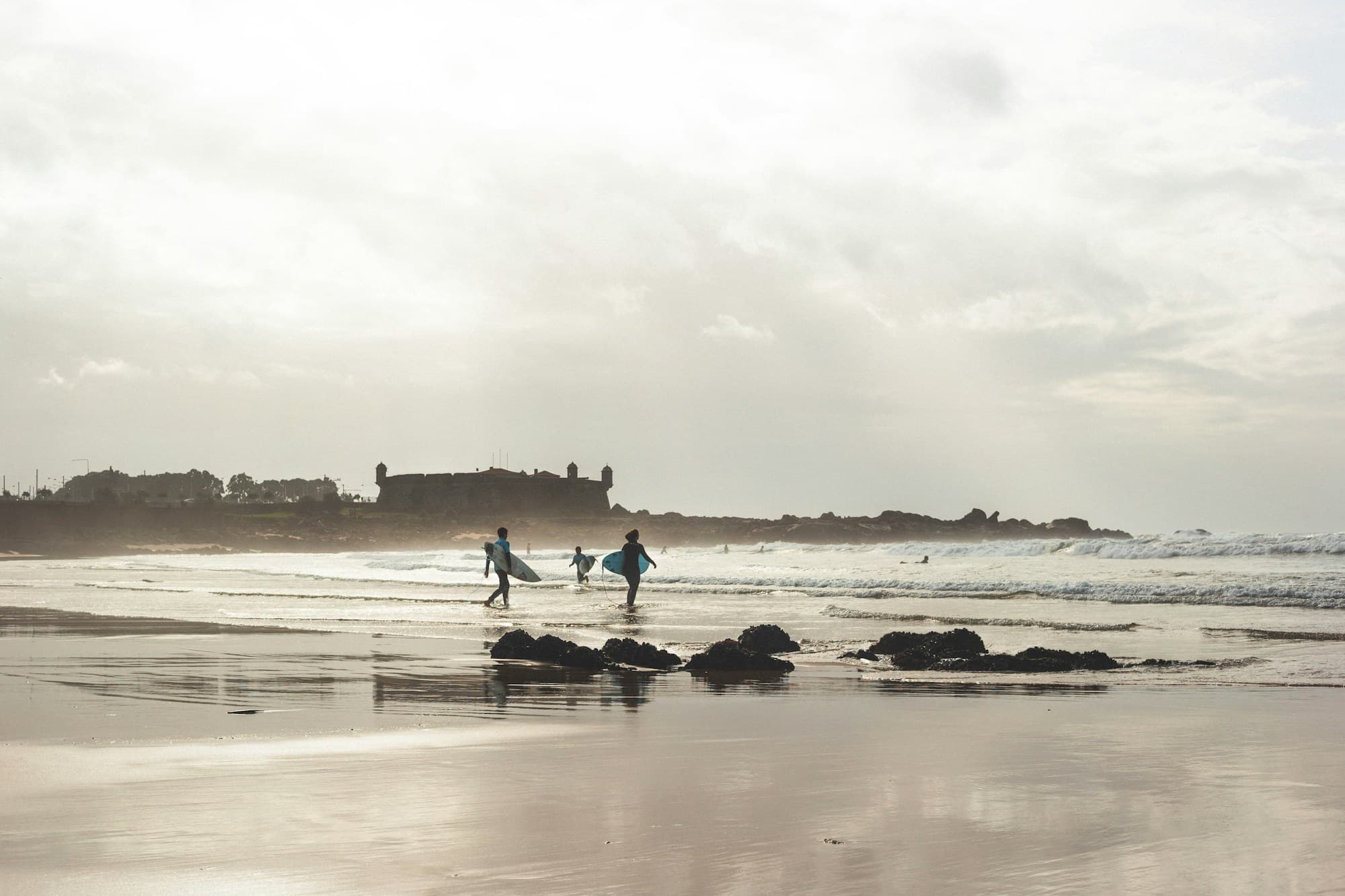 Surfers walking across Matosinhos Beach near Porto