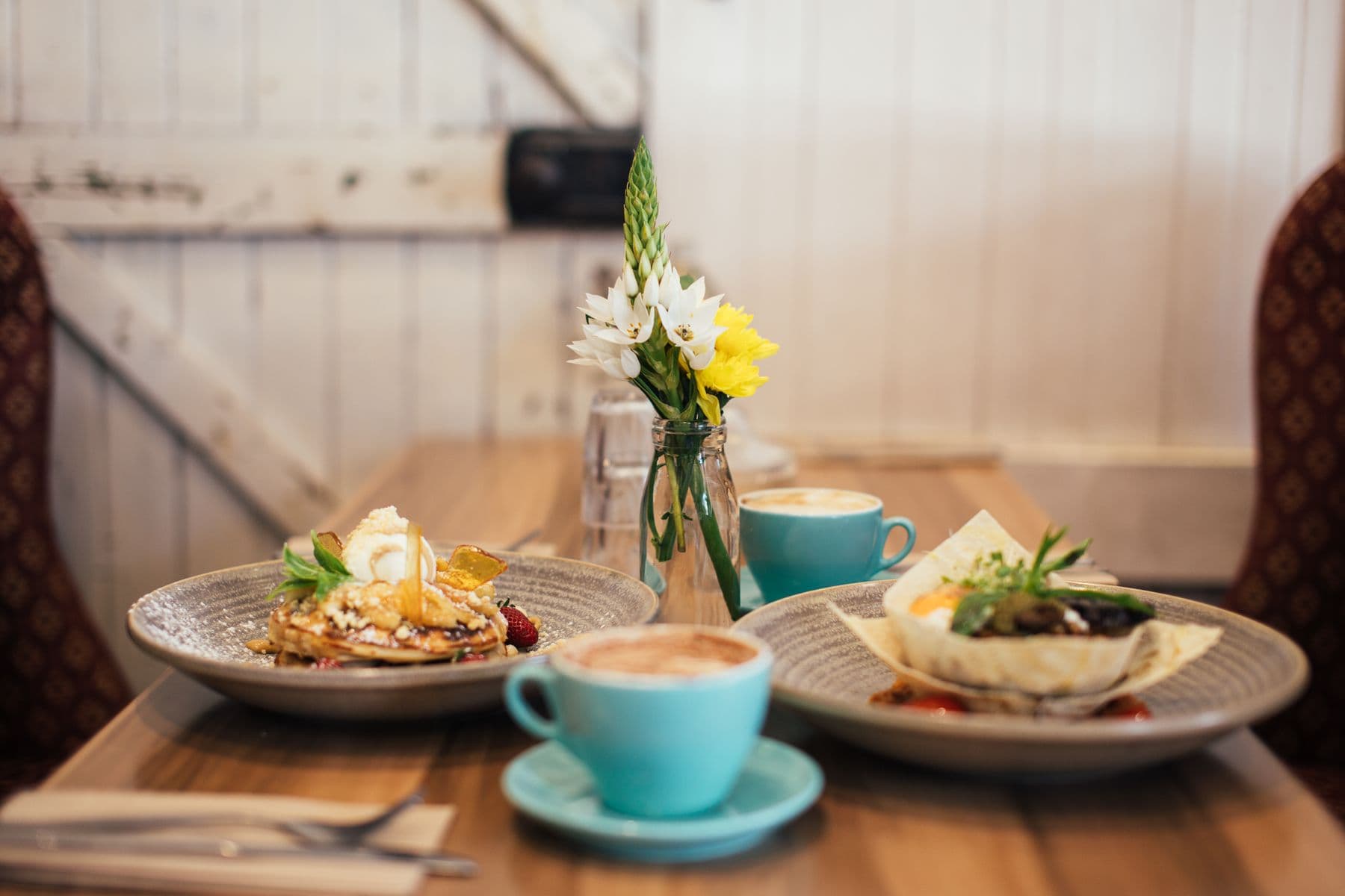 Coffee, pancakes and salad on a bright café table