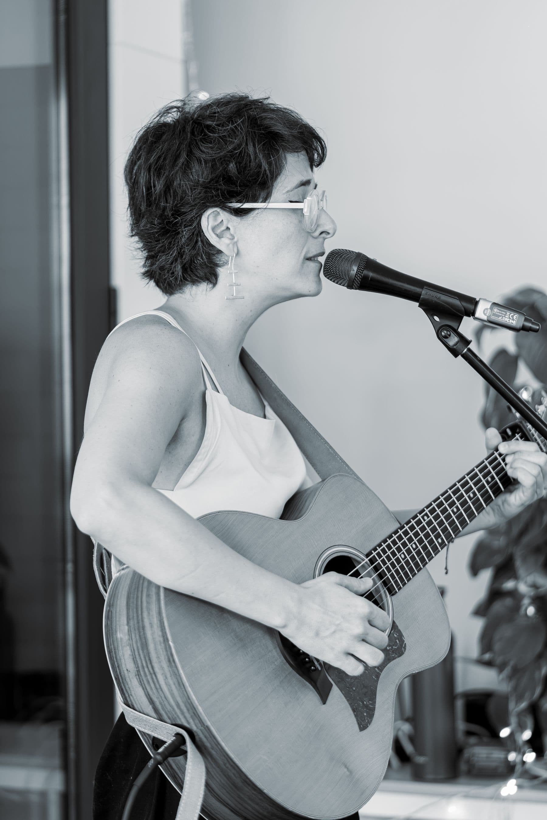 Woman singing and playing acoustic guitar indoors