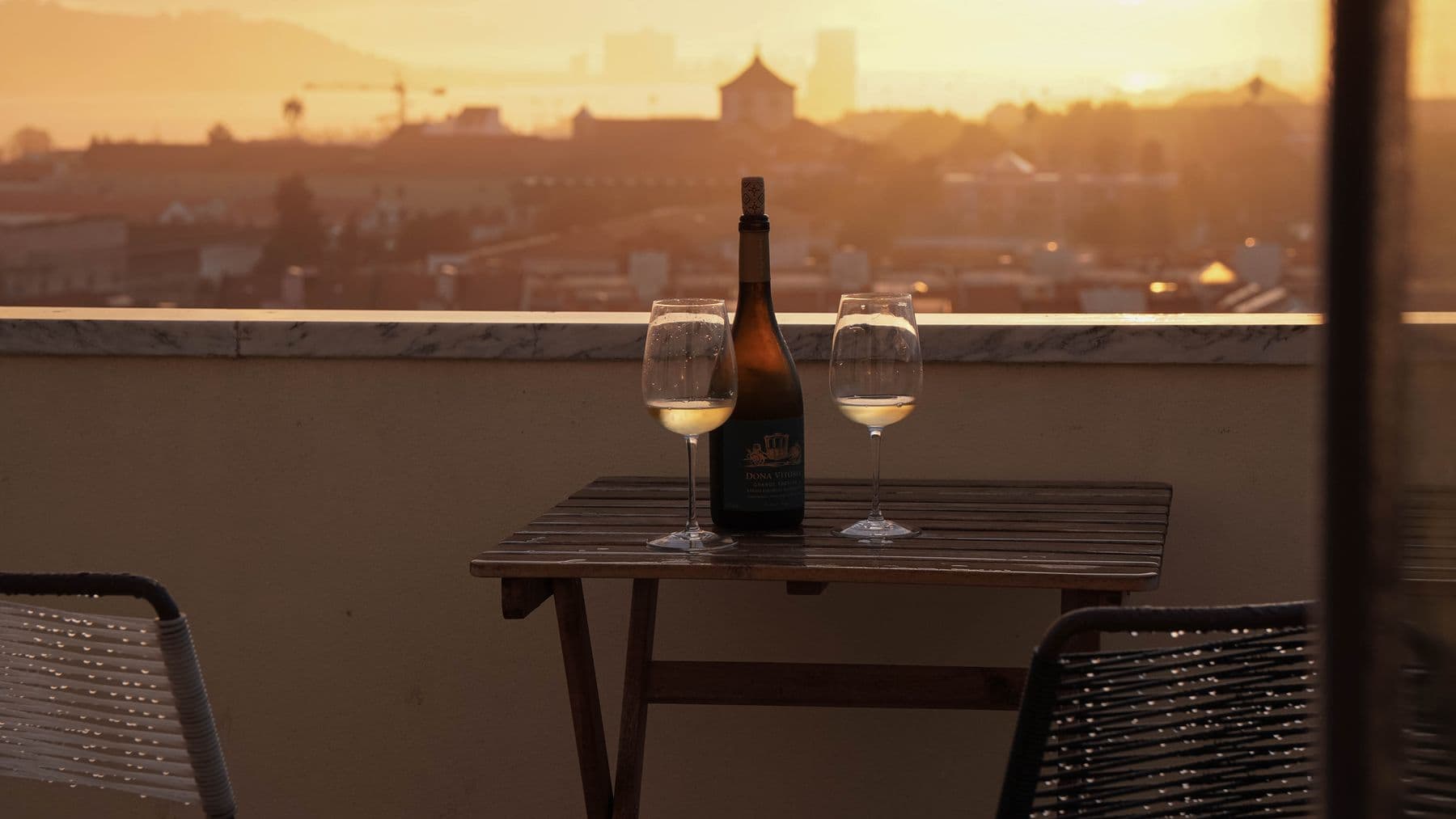 Wine bottle and glasses on a rooftop at sunset in Portugal
