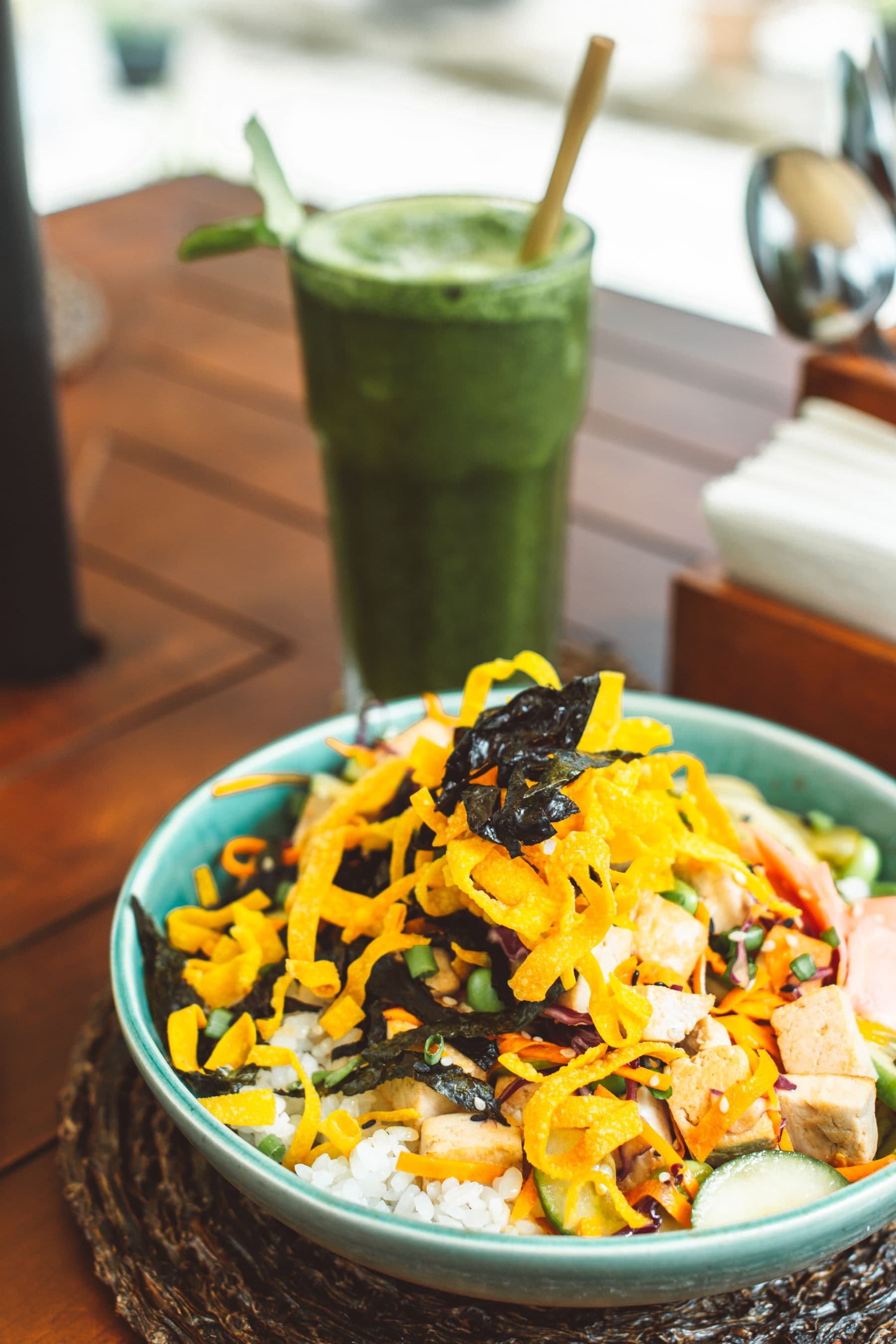 Plant-based poke bowl with fresh vegetables and a green drink