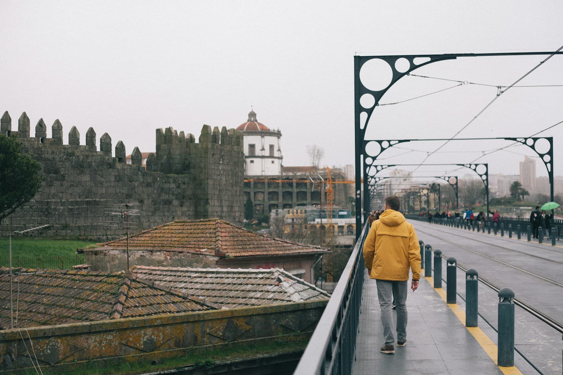 A traveller walking beside Porto's old city walls on a grey day